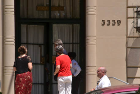 Picture of two women and two security officers at an imposing door that is starting to open